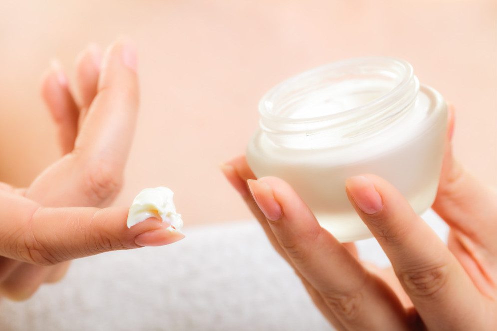 hands holding jar of  face cream